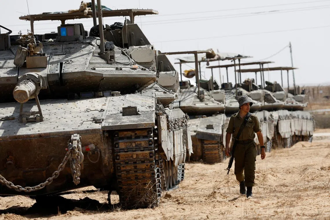 An Israeli soldier walks near tanks parked near the southern Israel-Gaza border on April 28, 2024. 