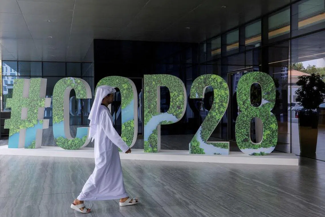 FILE PHOTO: A person walks past a \"#COP28\" sign during The Changemaker Majlis, a one-day CEO-level thought leadership workshop focused on climate action, in Abu Dhabi, United Arab Emirates, October 1, 2023. REUTERS/Amr Alfiky/File Photo