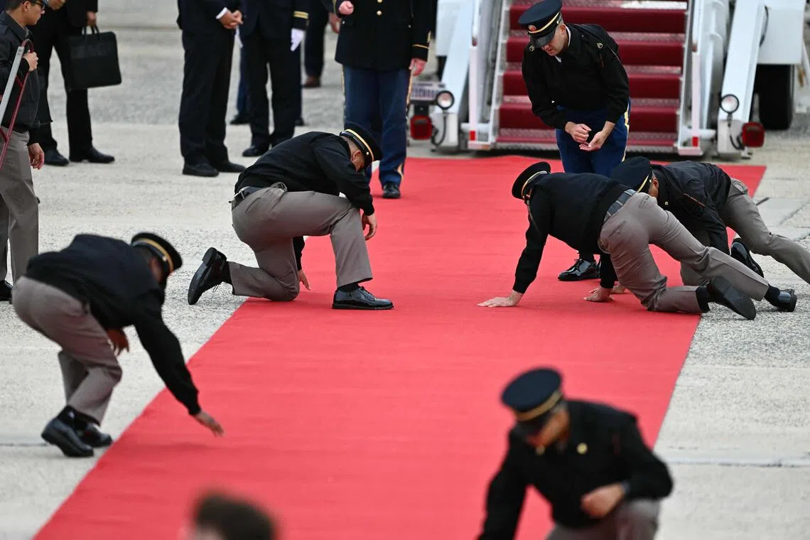 US military personnel got down on their knees to smooth the red carpet rolled out to welcome Chinese President Xi Jinping and his wife Peng Liyuan at Joint Base Andrews on Sept 23.