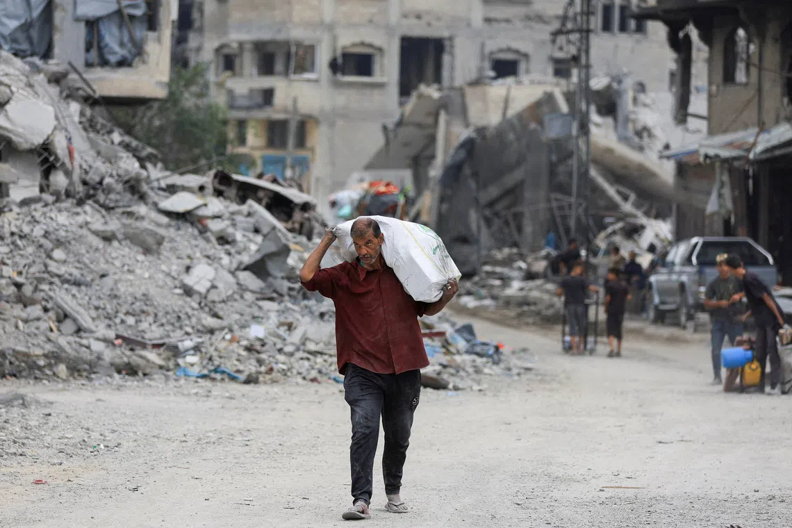 A Palestinian man walks past rubble following the withdrawal of the Israeli forces from the area, amid a ceasefire between Israel and Hamas in Gaza, in Gaza City, October 12, 2025. REUTERS/Dawoud Abu Alkas