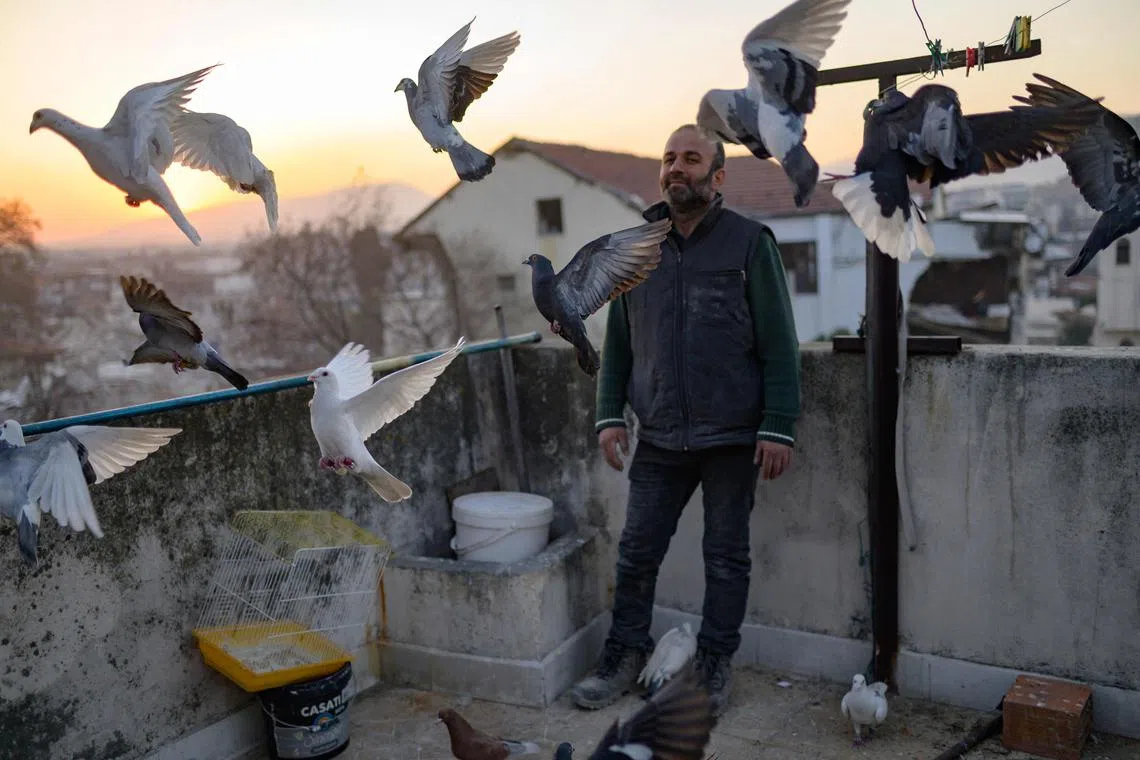 Murat Guzel scatters bird food on the roof of a restaurant where he worked before the earthquake, in Antakya south of Hatay, on February 17, 2023, after the 7.8-magnitude earthquake which struck parts of Turkey and Syria. - A 7.8-magnitude earthquake hit near Gaziantep, Turkey, in the early hours of February 6, followed by another 7.5-magnitude tremor just after midday. The quakes caused widespread destruction in southern Turkey and northern Syria and has killed more than 40,000 people. (Photo by Yasin AKGUL / AFP)