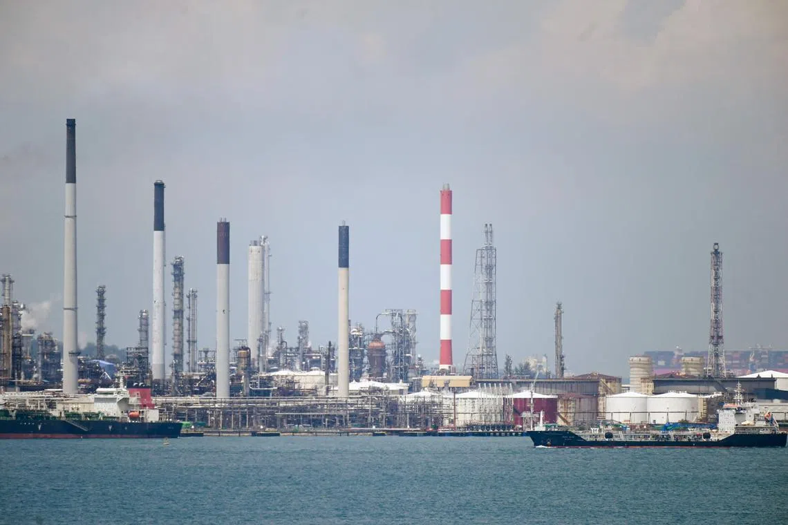 An oil tanker (R) sails past Shell petroleum refineries on Bukom Island off Singapore on March 17, 2022. (Photo by Roslan RAHMAN / AFP)