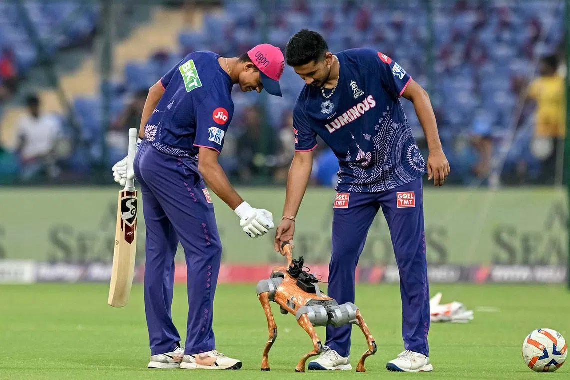 Rajasthan Royals' Yashasvi Jaiswal (left) and Kunal Singh Rathore playing with a robot dog before the start of the Indian Premier League Twenty20 cricket match between Delhi Capitals and Rajasthan Royals at the Arun Jaitley Stadium in New Delhi on April 16, 2025.