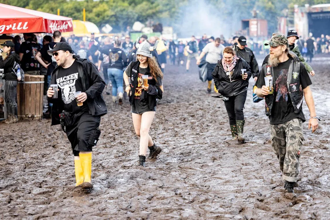 Visitors of the Wacken Open Air are fighting against the mud on the festival ground on August 1, 2023. Wacken Open Air, one of the largest heavy metal festivals in the world, will take place from August 2 until August 5, 2023. (Photo by Axel Heimken / AFP)