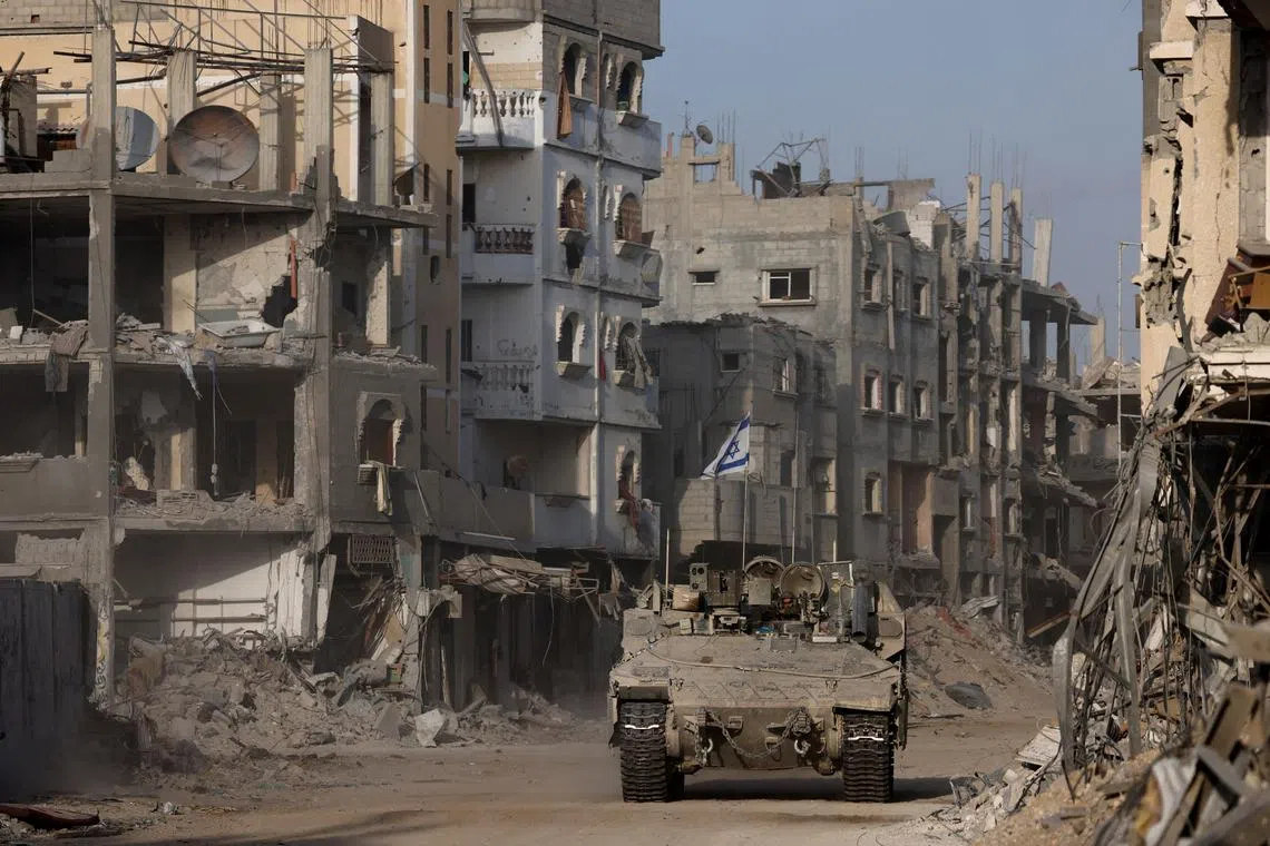 An armoured vehicle drives as damaged buildings are seen in the background, amid the ongoing ground operation of the Israeli army against Palestinian Islamist group Hamas, in the Gaza Strip, September 13, 2024. REUTERS/Amir Cohen/File Photo