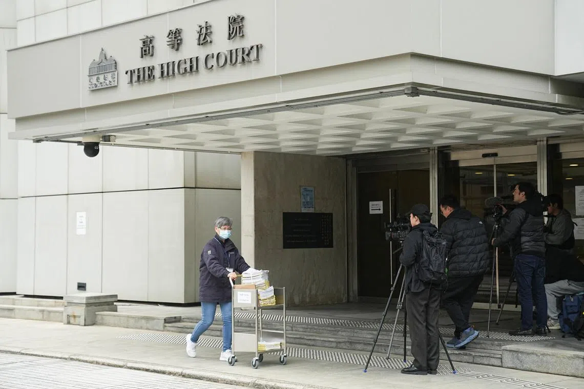A person pushes a cart near media members standing outside the High Court where a court hearing on property developer China Evergrande Group is held, in Hong Kong, China January 29, 2024. REUTERS/Lam Yik