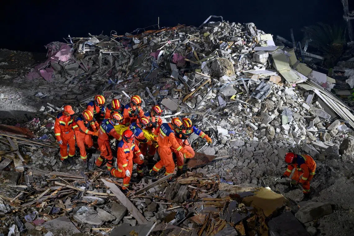 Rescue workers carry a casualty as they search for survivors at the site of a landslide along the Wujiang river in Chongqing.
