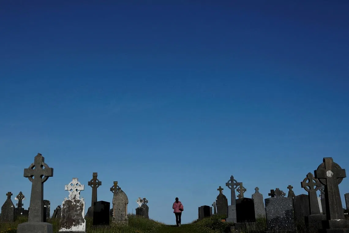 A woman walking through a graveyard, in the County Galway village of Furbo, Ireland May 16.