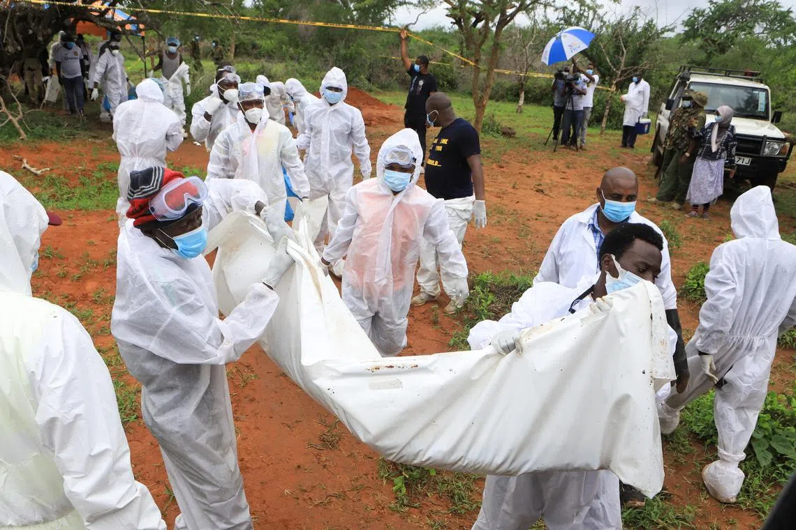 Forensic experts and homicide detectives carry the bodies of suspected members of a Christian cult named as Good News International Church, who believed they would go to heaven if they starved themselves to death, after their remains were exhumed from their graves in Shakahola forest of Kilifi county, Kenya April 22, 2023. REUTERS/Stringer
