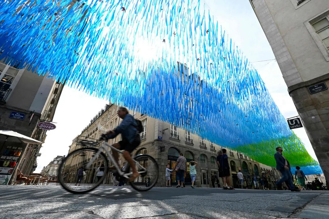 A man riding his bicycle under a shading device to fight excessive heat on a downtown shopping street in Rennes, western France, on July 20, 2023, as Europe is hit by a major heatwave.