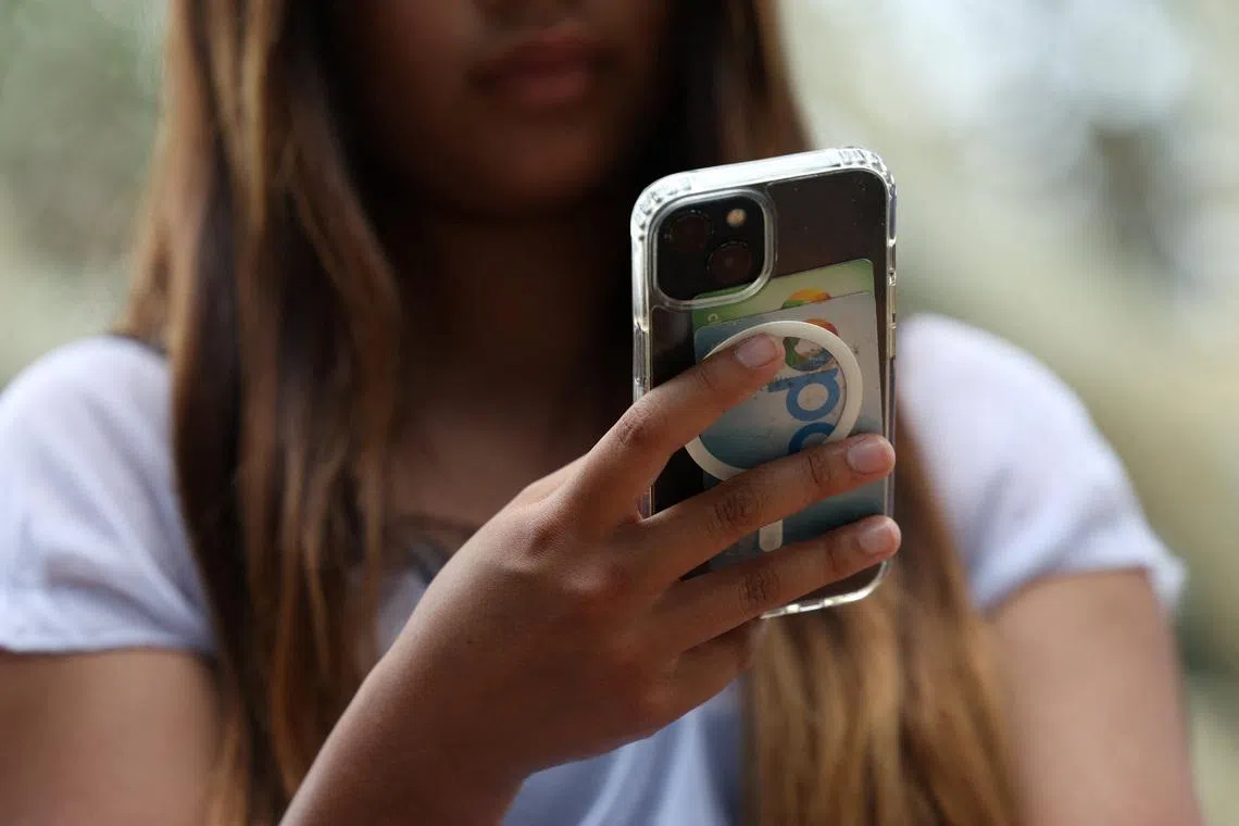 A teenager poses holding a mobile phone as law banning social media for users under 16 in Australia takes effect, in Sydney, Australia, December 10, 2025. REUTERS/Hollie Adams/File Photo