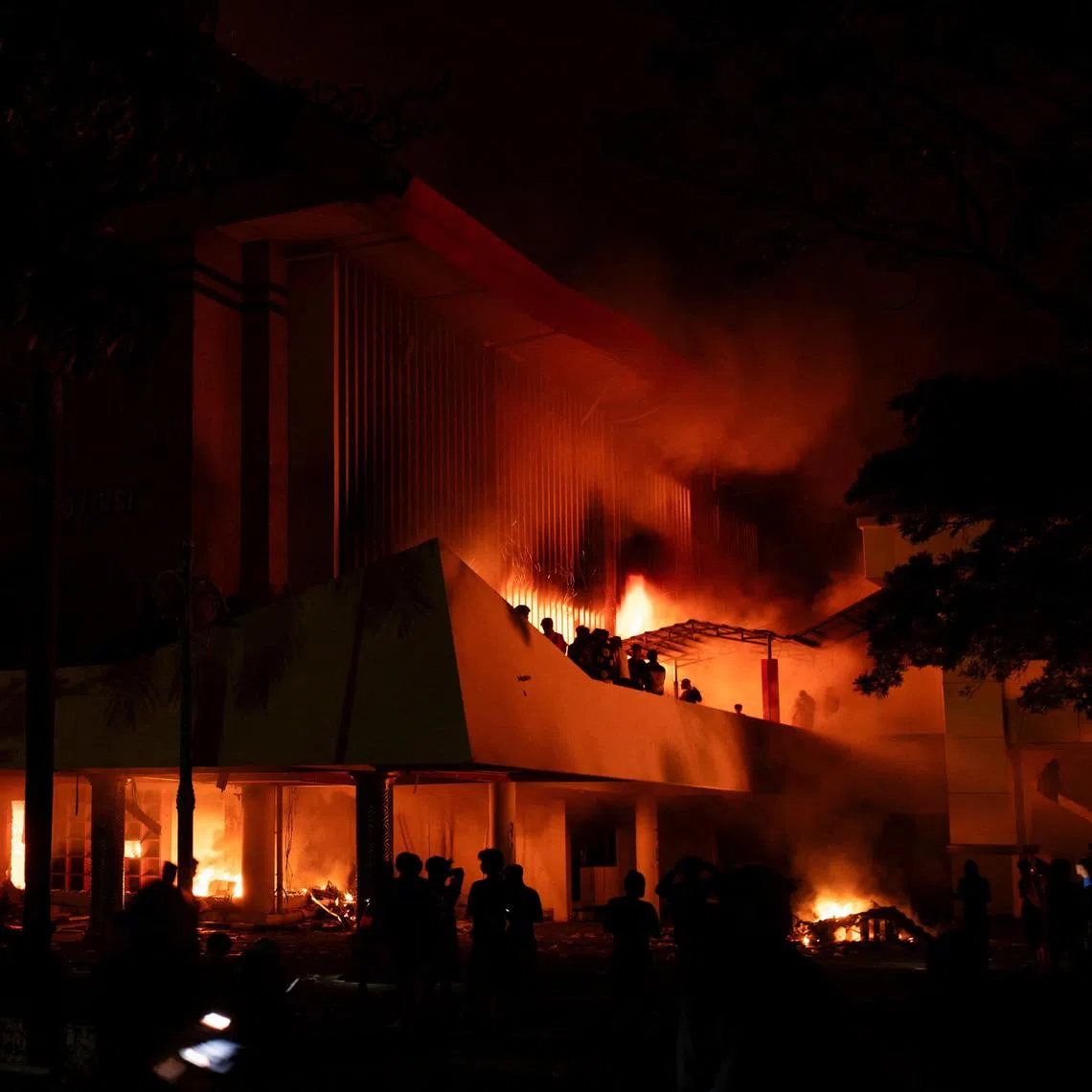 Protesters gather near the burning regional parliament building, during a protest after a motorcycle taxi driver died after being struck and run over by a police tactical vehicle during Thursday's protest against parliamentarians' allowances, in Makassar, South Sulawesi province, Indonesia, August 30, 2025. REUTERS/Iqbal Lubis