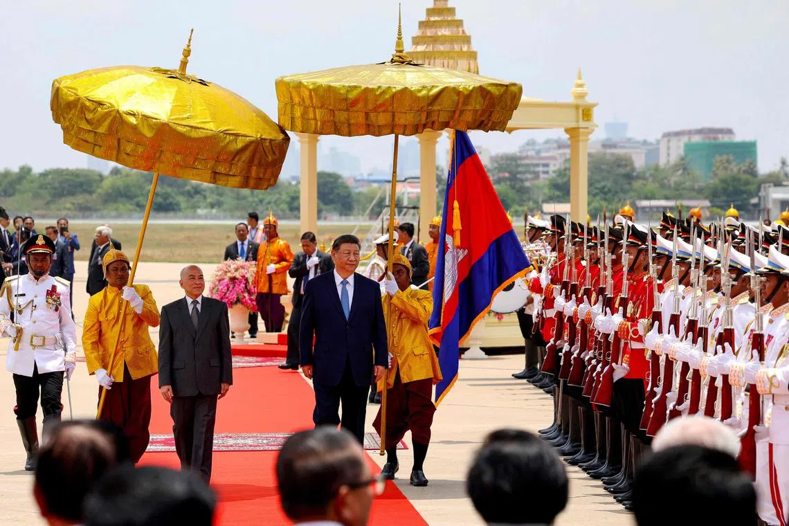 China's President Xi Jinping (centre) and Cambodia's King Norodom Sihamoni (centre-left) walking past the honour guards upon arrival at Phnom Penh International Airport on April 17.