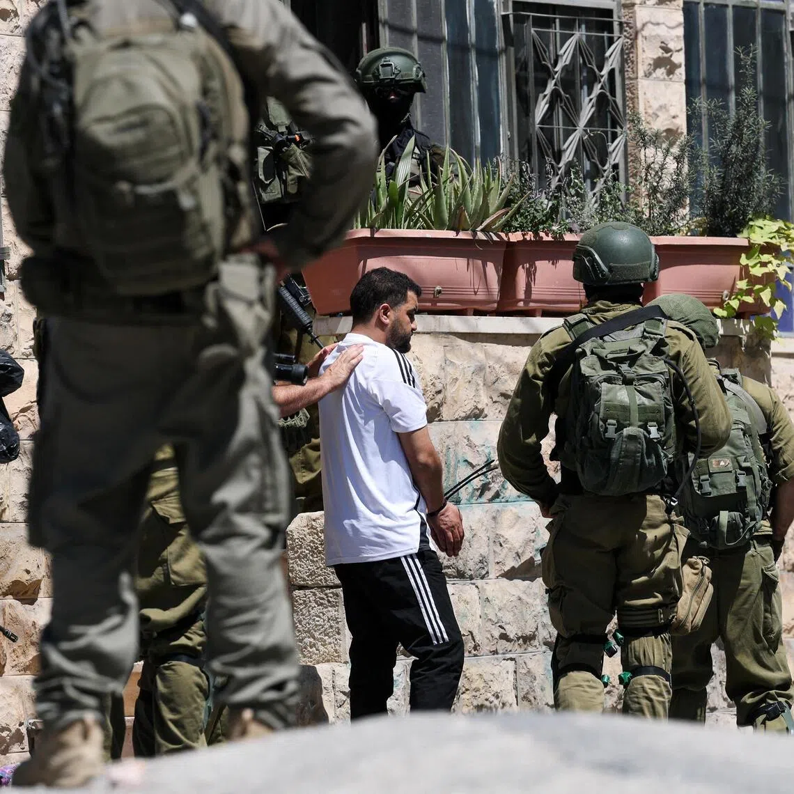 Israeli soldiers talking to a Palestinian man, as they conduct a raid in Anata, in the Israeli-occupied West Bank, on Sept 8.