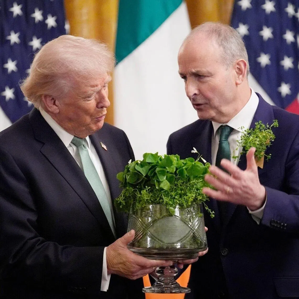 US President Donald Trump (left) receives a bowl of shamrocks from Irish Prime Minister Micheal Martin (right) to celebrate St. Patrick's Day at the White House.