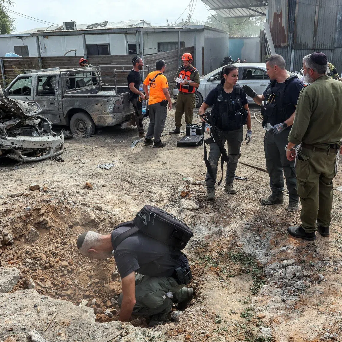 A security official investigates the crater formed when a projectile landed, after Hamas' armed wing said it attacked Tel Aviv with a missile salvo, amid the ongoing Israel-Hamas conflict, in Kfar Chabad, Israel, October 7, 2024. REUTERS/Itai Ron/File Photo