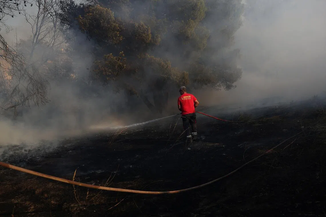 FILE PHOTO: A man tries to extinguish a wildfire burning near Anavyssos, near Athens, Greece August 8, 2025. REUTERS/Stelios Misinas/File Photo