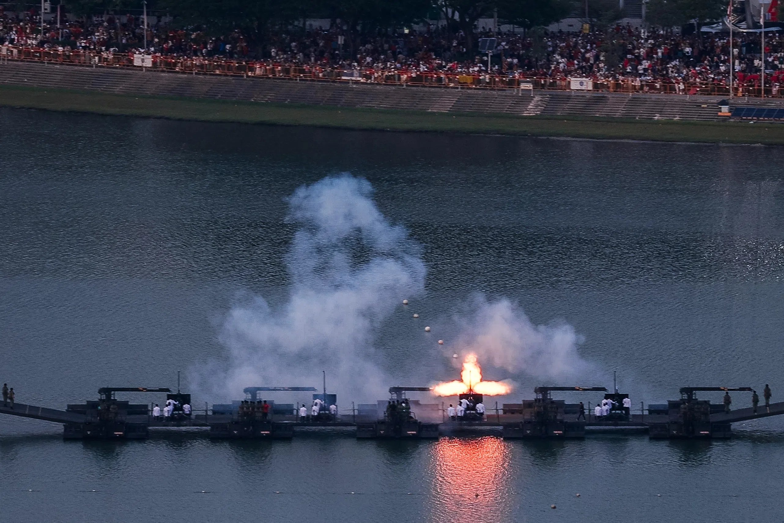 //** MUST INCLUDE “SUNTEC CITY” IN CAPTION OR LOCATION TAG **// One of the 25-pounder howitzers fires during the 21-gun Presidential Gun Salute at Kallang Basin during the National Day Parade 2026 at the National Stadium, as seen from Suntec City on Aug 9, 2026. ST PHOTO: GAVIN FOO