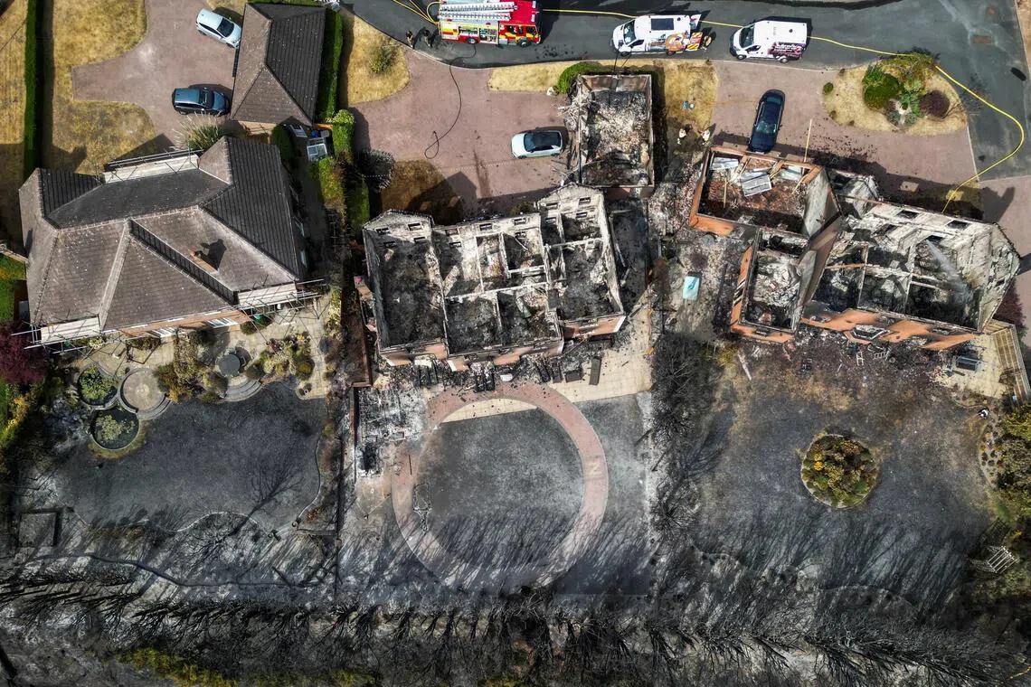 Aerial view of a burnt-out house with fire trucks parked on the street.