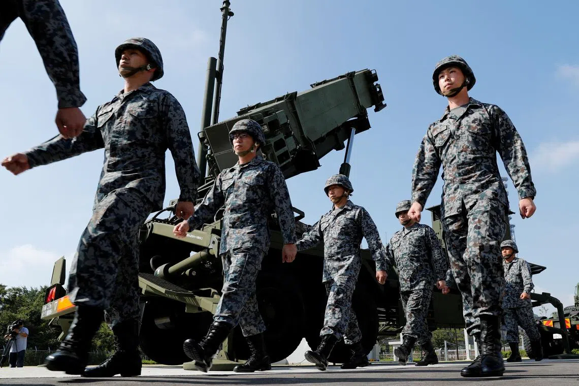 FILE PHOTO: Japan Self-Defense Forces (JSDF) soldiers walk past a Patriot Advanced Capability-3 (PAC-3) missile unit after Japan's Chief Cabinet Secretary Yoshihide Suga (L) reviews the unit at the Defense Ministry in Tokyo, Japan, October 8, 2017. REUTERS/Kim Kyung-Hoon/File Photo