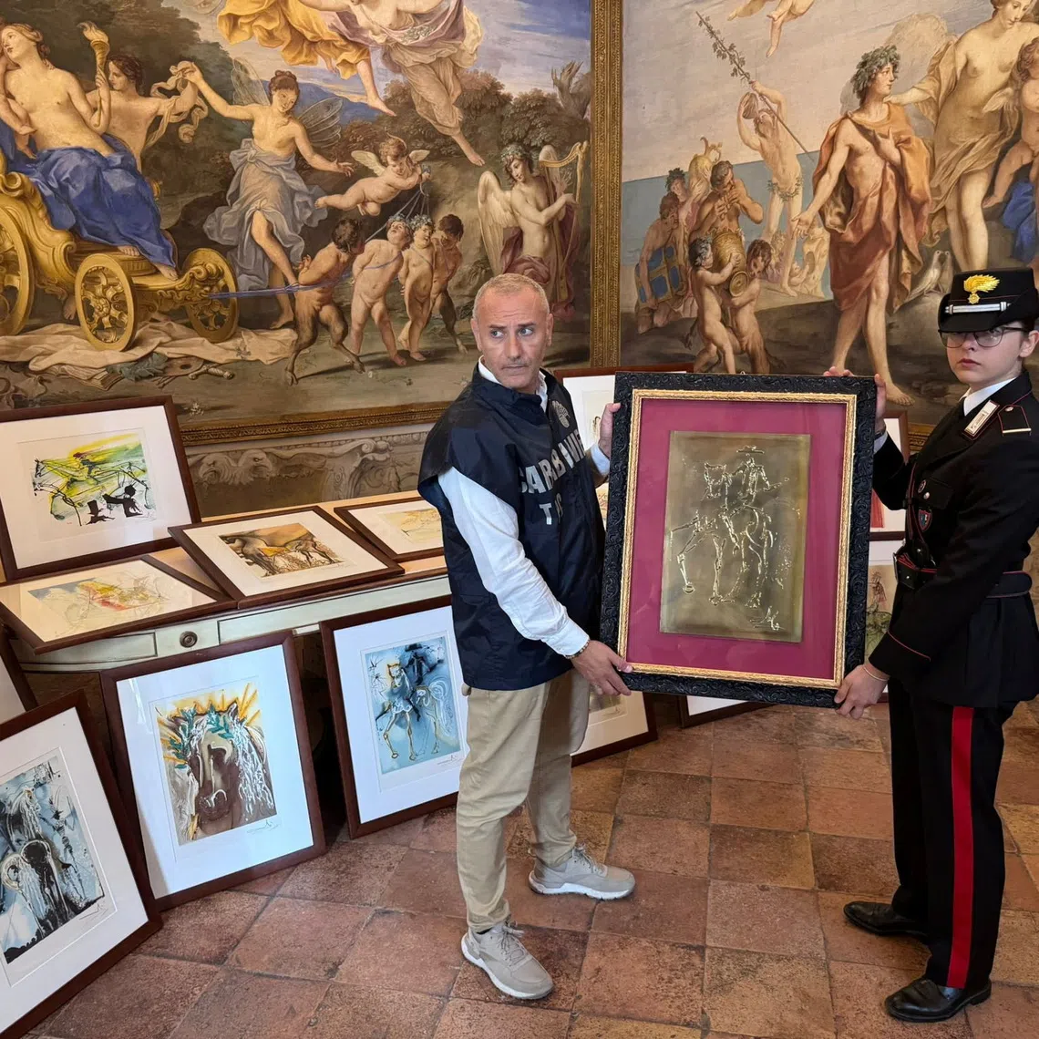 Carabinieri officers hold one of the 21 artworks presumed to be inauthentic and falsely attributed to Salvador Dali, seized during an exhibition in Parma following an investigation by the Rome Public Prosecutor's Office, in Rome, Italy, in this handout picture obtained on October 1, 2025. Carabinieri/Handout via REUTERS    THIS IMAGE HAS BEEN SUPPLIED BY A THIRD PARTY