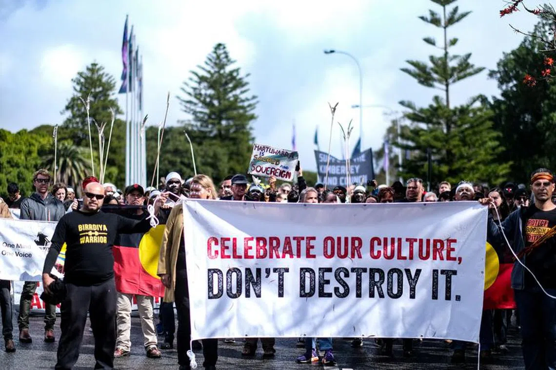 FILE PHOTO: Aboriginal groups' members carrying a banner march to protest against what they say is a lack of detail and consultation on new heritage protection laws, after the Rio Tinto mining group destroyed ancient rock shelters for an iron ore mine last year, in Perth, Australia August 19, 2021. Courtesy Gabrielle Timmins/Kimberley Land Council/Handout via REUTERS/File Photo
