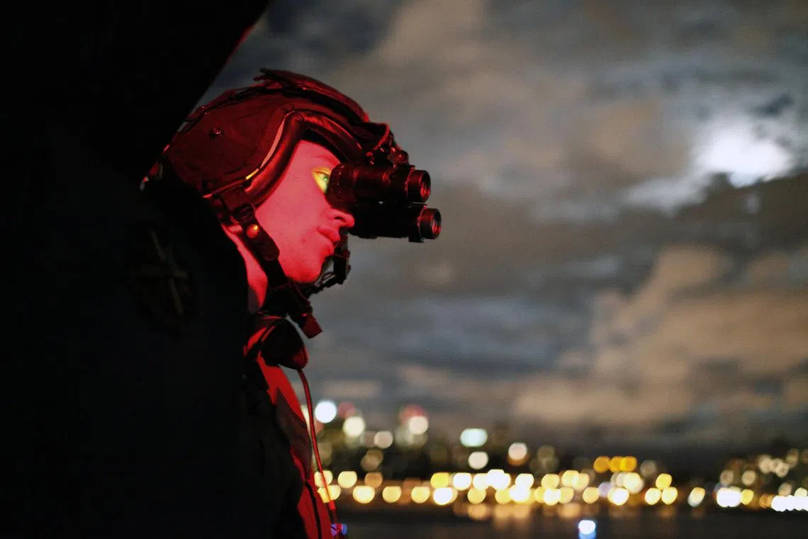 Marine Cpl.Bob Johnson looks through night vision goggles while flying in a presidential support helicopter during President Barack Obama's campaign trip to New York, June 4, 2012. 