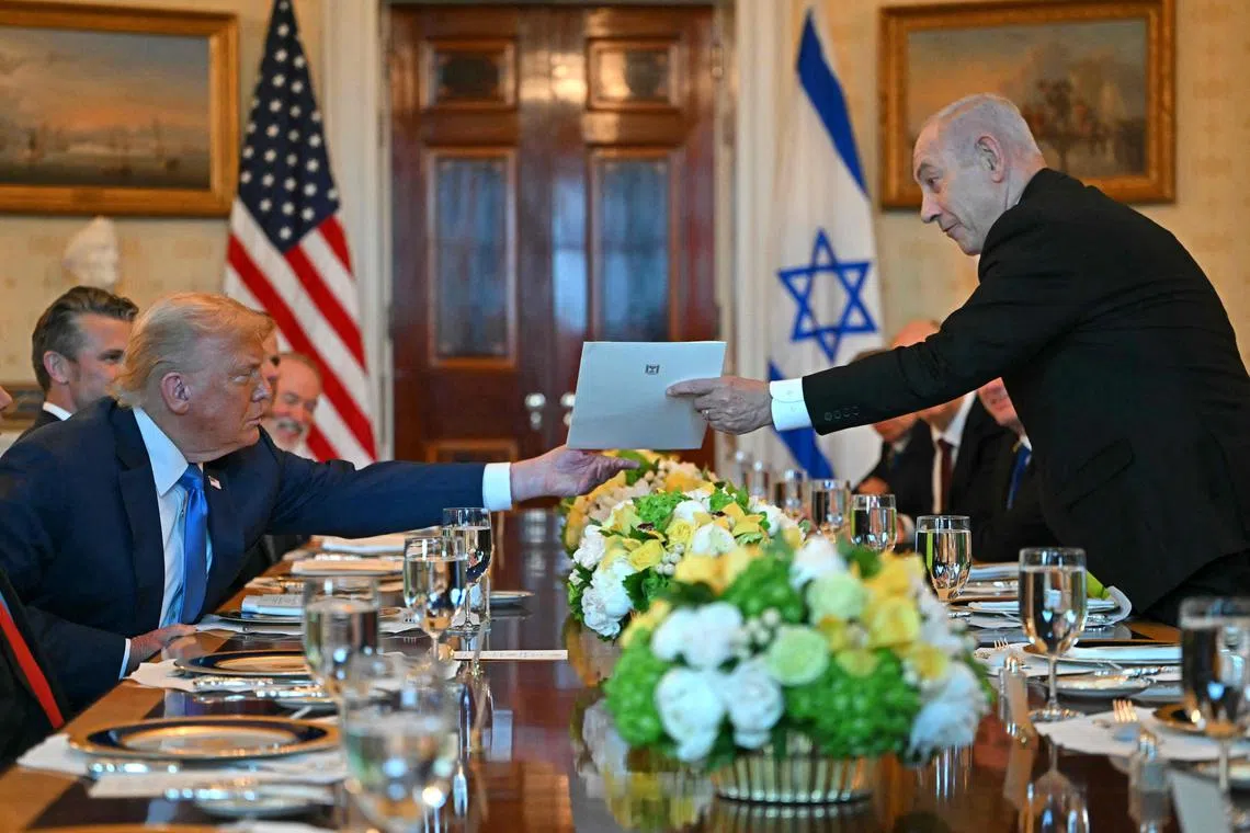 Israeli Prime Minister Benjamin Netanyahu (right) hands over a letter to US President Donald Trump as they meet at the Blue Room of the White House, on July 7.