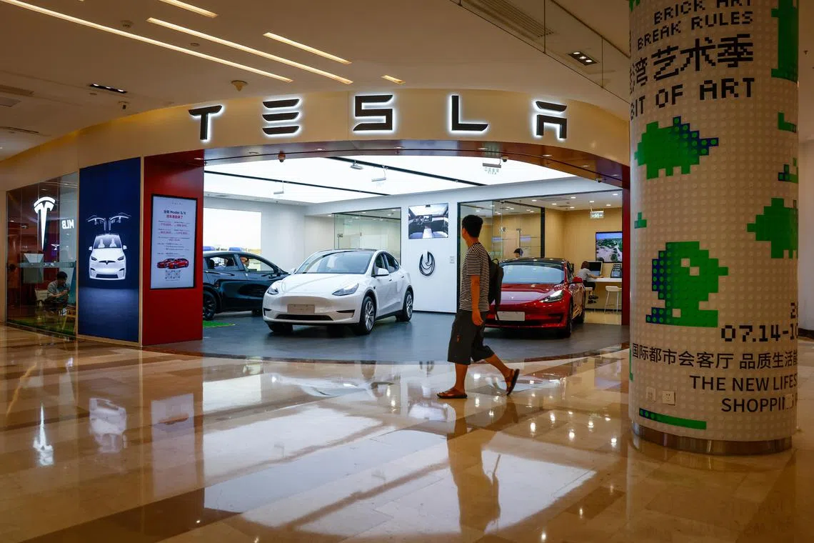 A man walks next to a Tesla showroom in Beijing, China.