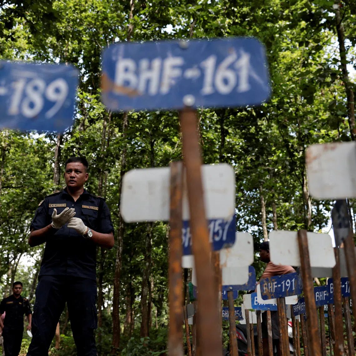 A police officer stands near identification number tags for bodies at the Devghat mass burial site for victims of deadly flash floods and mudslides, in Chitwan, Nepal, August 30, 2026. REUTERS/Navesh Chitrakar