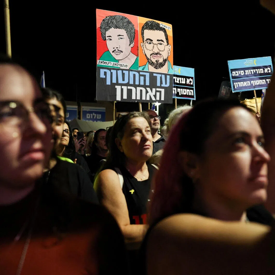 Demonstrators hold images of dead hostages Ran Gvili and Sudthisak Rinthalak, who were killed in the Oct 7, 2023 Hamas attack.