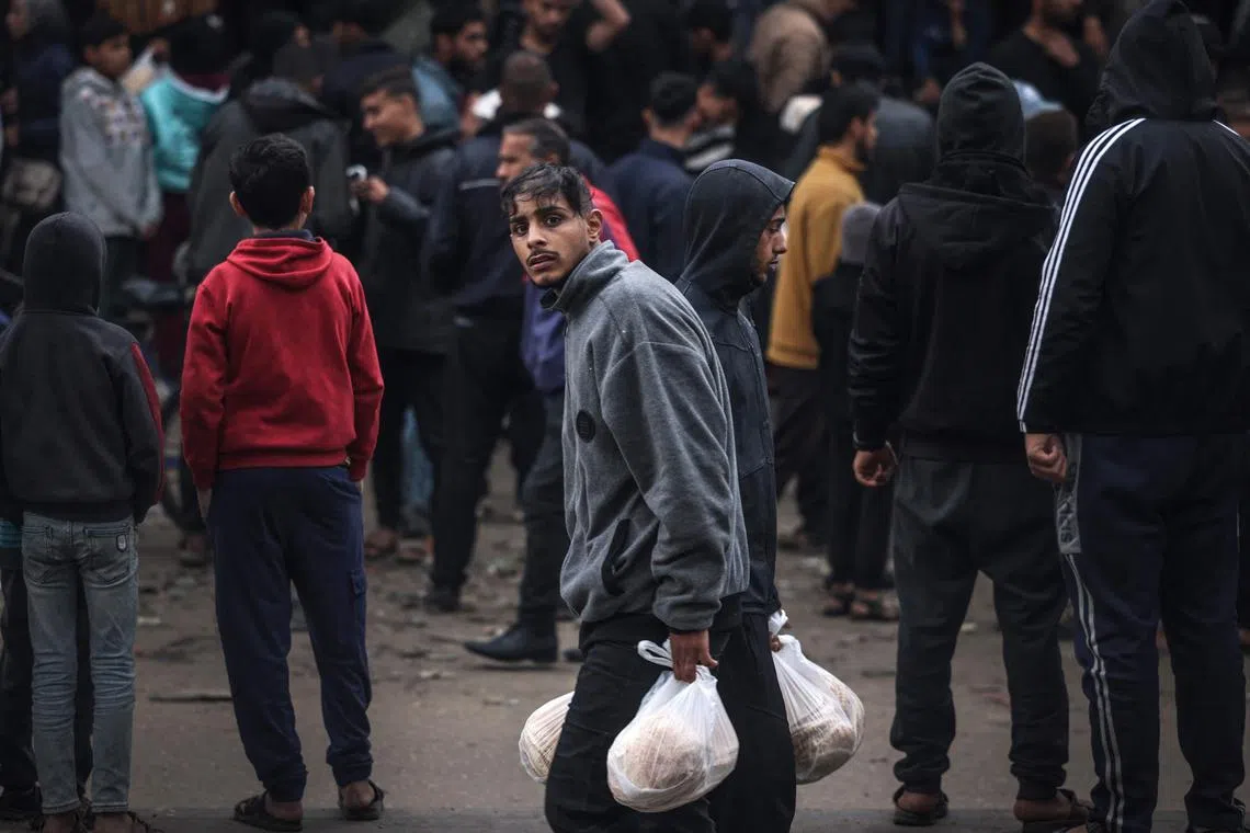 A man walks with bags of freshly bought bread in Rafah, in the southern Gaza Strip. Some 1.4 million people have fled to Rafah, amid Israel's military action in Gaza. 