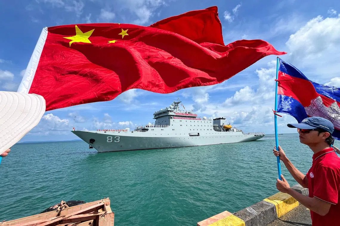 People wave flags of Cambodia (R) and China (L) as Chinese training ship Qijiguang prepares to dock with a banner reading "Bring peace and friendship to meet good friends" during a welcome ceremony at the Sihanoukville port in Preah Sihanouk province on May 19, 2024. Two Chinese warships docked in Cambodia on May 19, 2024 as part of the biggest-ever joint military drills with the Southeast Asian nation. (Photo by AFP)