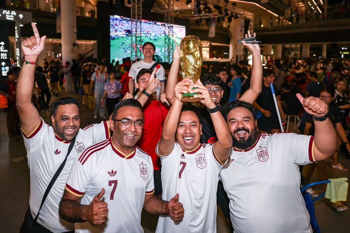 Spanish fans celebrating with a replica of the World Cup trophy after the full-time whistle during the live screening of the FIFA World Cup 2026 final between Argentina and Spain at Our Tampines Hub in the early hours of July 20, 2026. Spain won the game 1-0. ST PHOTO: BRIAN TEO