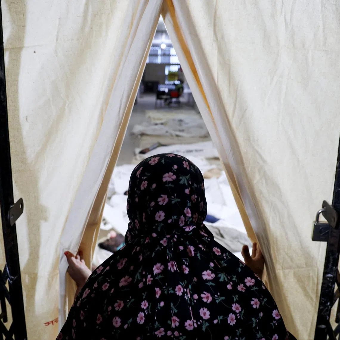 A woman looks towards the bodies of the victims of a bus accident at a mortuary in Bangladesh.