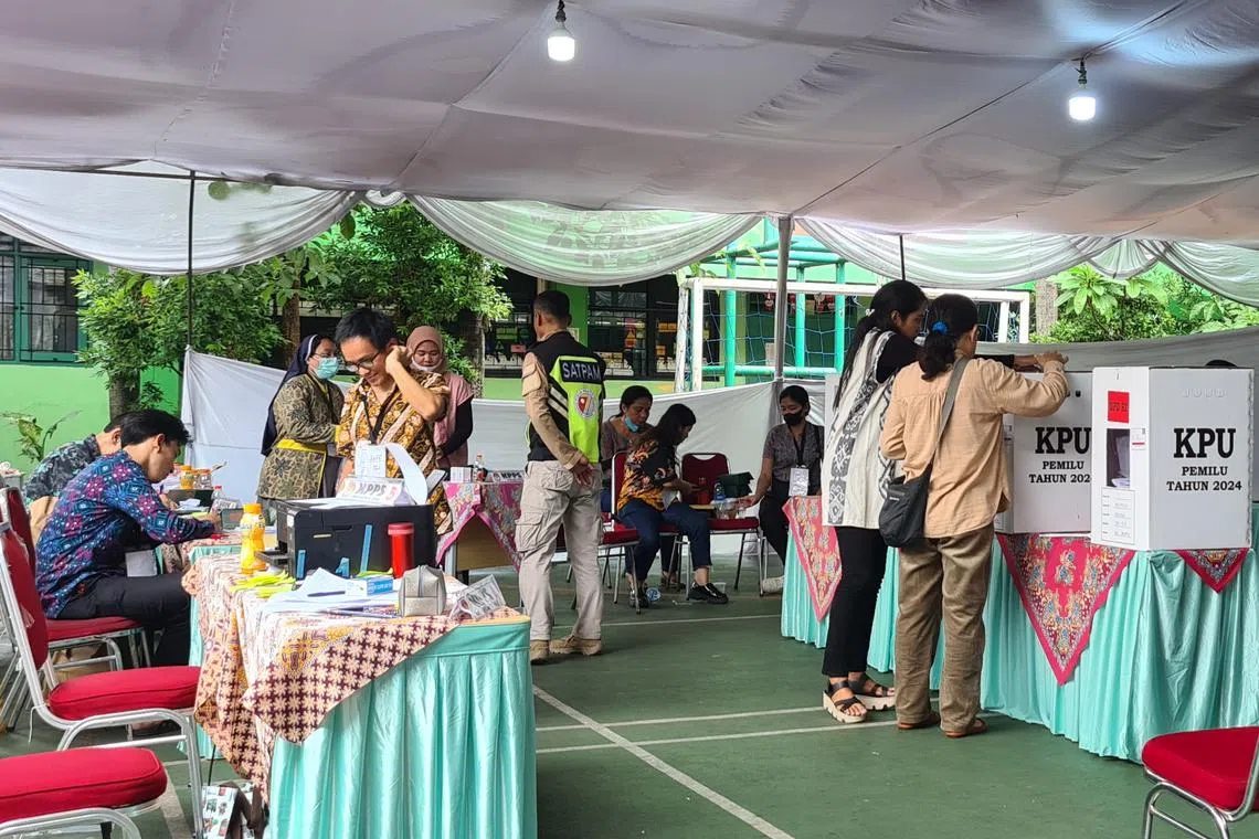 Voters putting ballot cards into a box at a polling station in Jakarta.