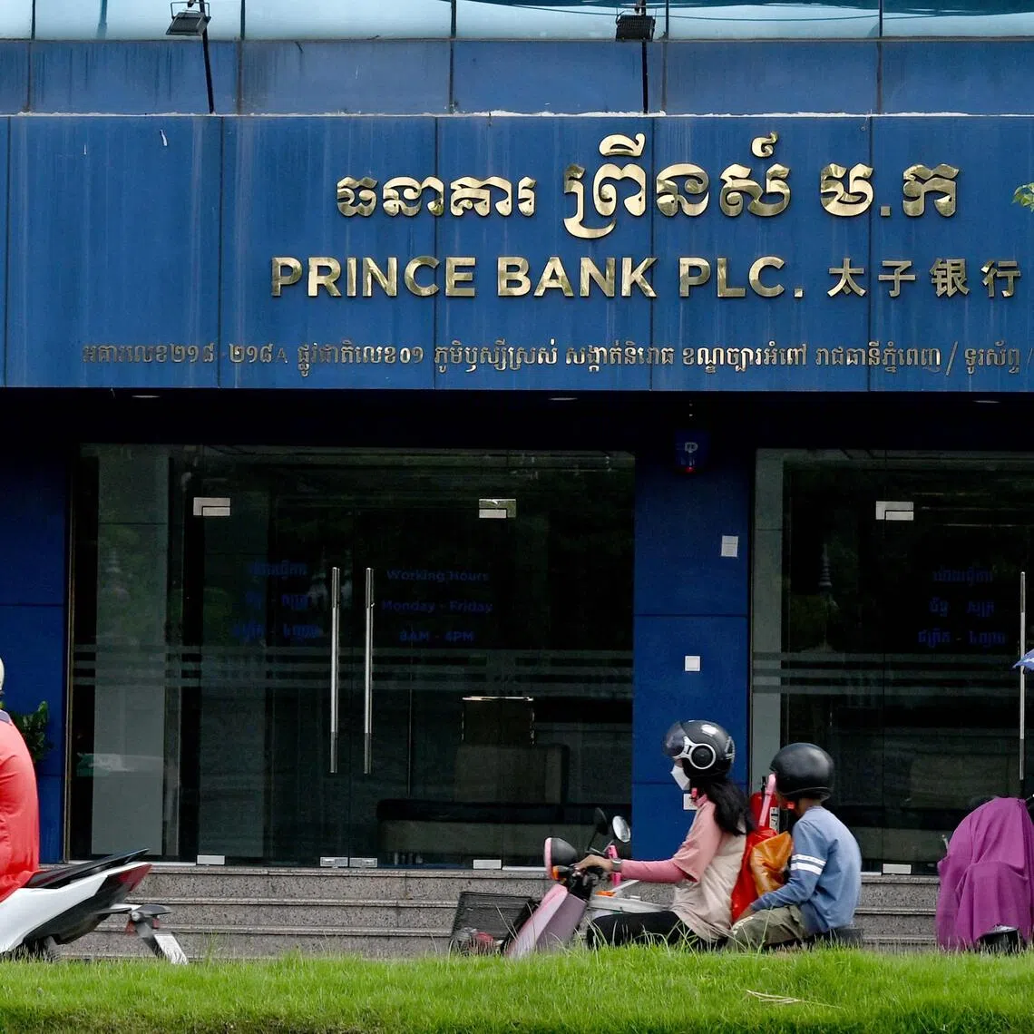 Motorists ride past a branch of the Prince Bank in Phnom Penh on Oct 15.