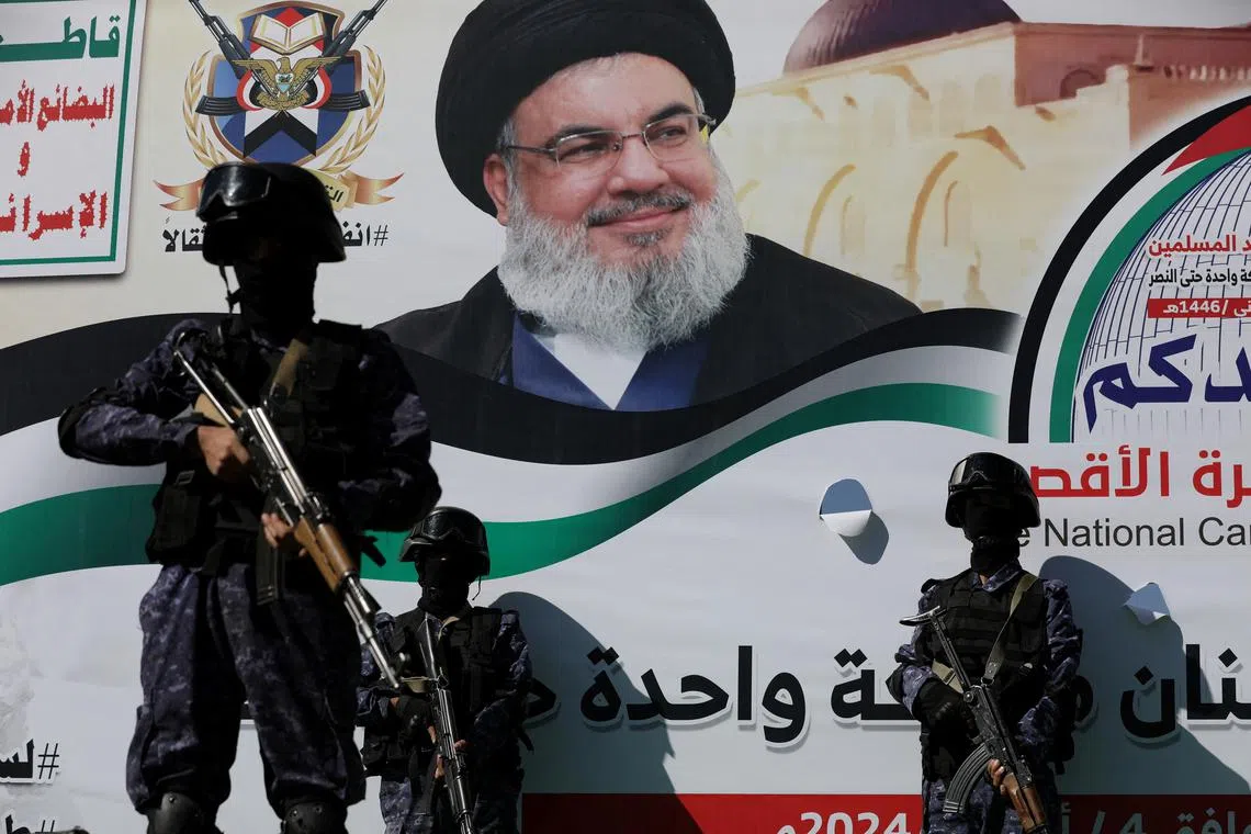 FILE PHOTO: Soldiers stand guard near a poster of the late leader of Lebanon's Hezbollah, Hassan Nasrallah, during a rally to commemorate him and to show support to Palestinians in the Gaza Strip, in Sanaa, Yemen October 4, 2024. REUTERS/Khaled Abdullah/File Photo