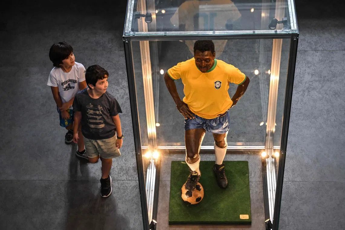 Visitors looking at a wax figure of Brazil's football legend Pele at the Pele Museum, in Santos, Brazil, on Dec 27, 2022.