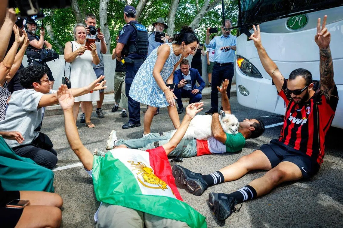 Members of the Iranian community in Australia block the path of a departing bus transporting members of the Iranian Women’s Asia Cup football team to the airport, outside the Royal Pines Resort on the Gold Coast on March 10, 2026. Five players in Iran's visiting women's football team have taken asylum in Australia over fears of persecution at home for not singing the national anthem before a match, the Australian government said on March 10. 