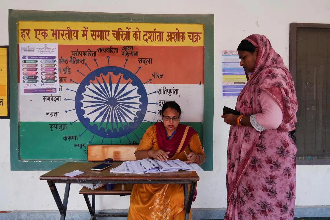 A booth-level officer helps a woman verify her name in the voting list outside a polling station during the state assembly elections, in Karnal, in the northern state of Haryana, India, October 5, 2024. REUTERS/Bhawika Chhabra/File Photo