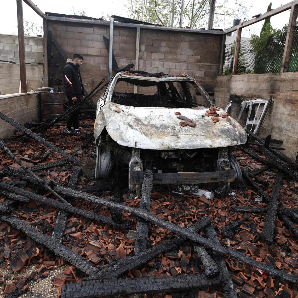 A Palestinian inspects a burnt-out car following an attack by Israeli settlers in the village of Deir al-Hatab in the Israeli-occupied West Bank on March 23, 2026. 
