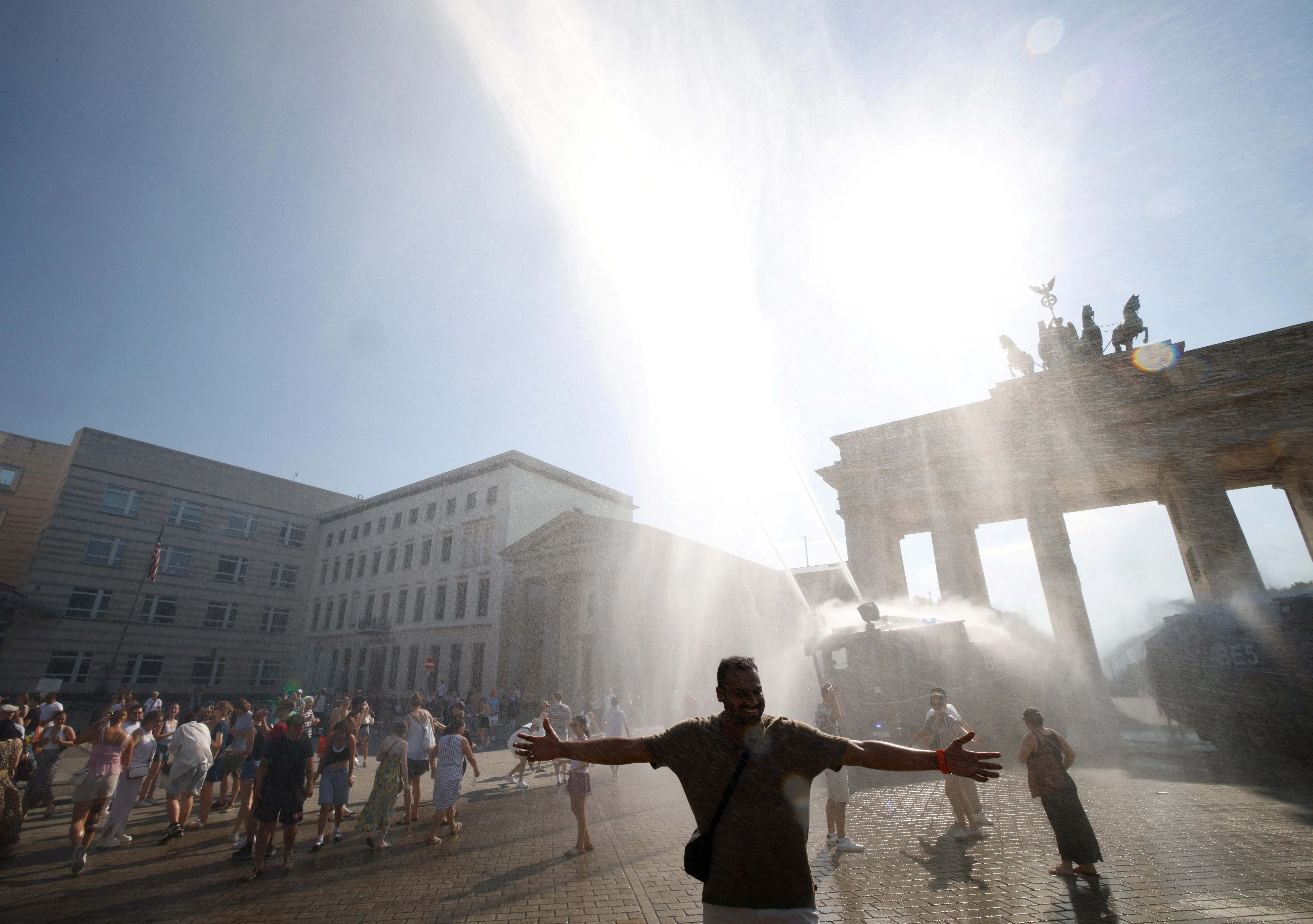 People enjoy the water sprayed by a police water cannon at the Brandenburg Gate during the ongoing heatwave in Berlin, Germany, June 27, 2026. REUTERS/Axel Schmidt