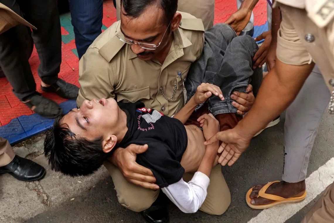 Police officers helping a stampede victim as he gasps to breathe near the stadium in Bengaluru on June 4.