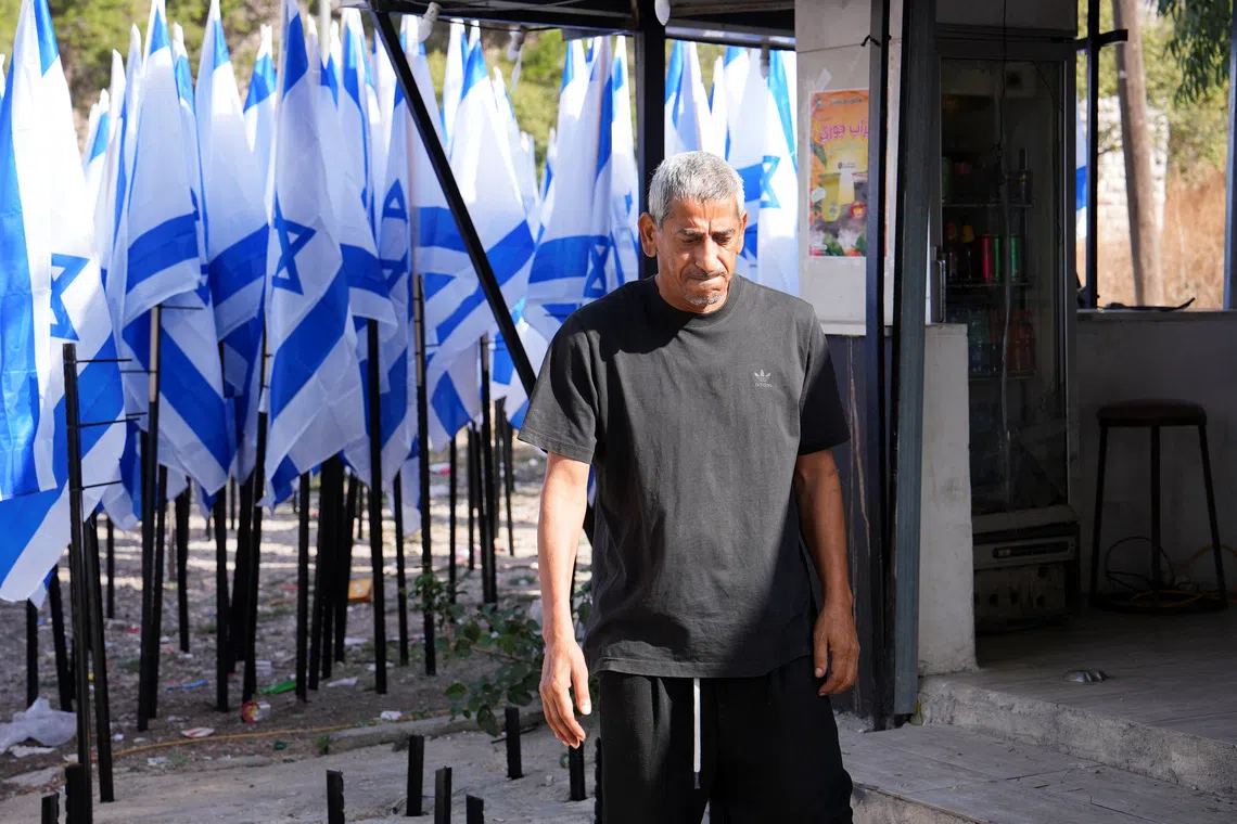 Palestinian coffee shop owner Mueiyyid Hussein outside his  business in the Israeli-occupied West Bank on Oct 9. Israeli settlers have planted dozens of Israeli flags at the entrance to his streetside cafe.
