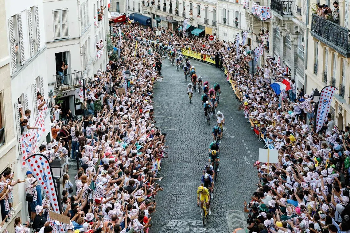 TOPSHOT - UAE Team Emirates - XRG's Slovenian rider Tadej Pogacar wearing the overall leader's yellow jersey leads the pack of riders (peloton) up Rue Lepic on the ascent of the Butte de Montmartre during the 21st stage of the 113th edition of the Tour de France cycling race, 88,7 km starting and finishing in Paris, on July 26, 2026. (Photo by GEOFFROY VAN DER HASSELT / AFP)