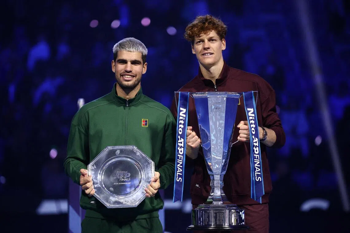 Italy's Jannik Sinner celebrates with the trophy after winning the final of the ATP Finals as Spain's Carlos Alcaraz poses with the runners-up trophy.