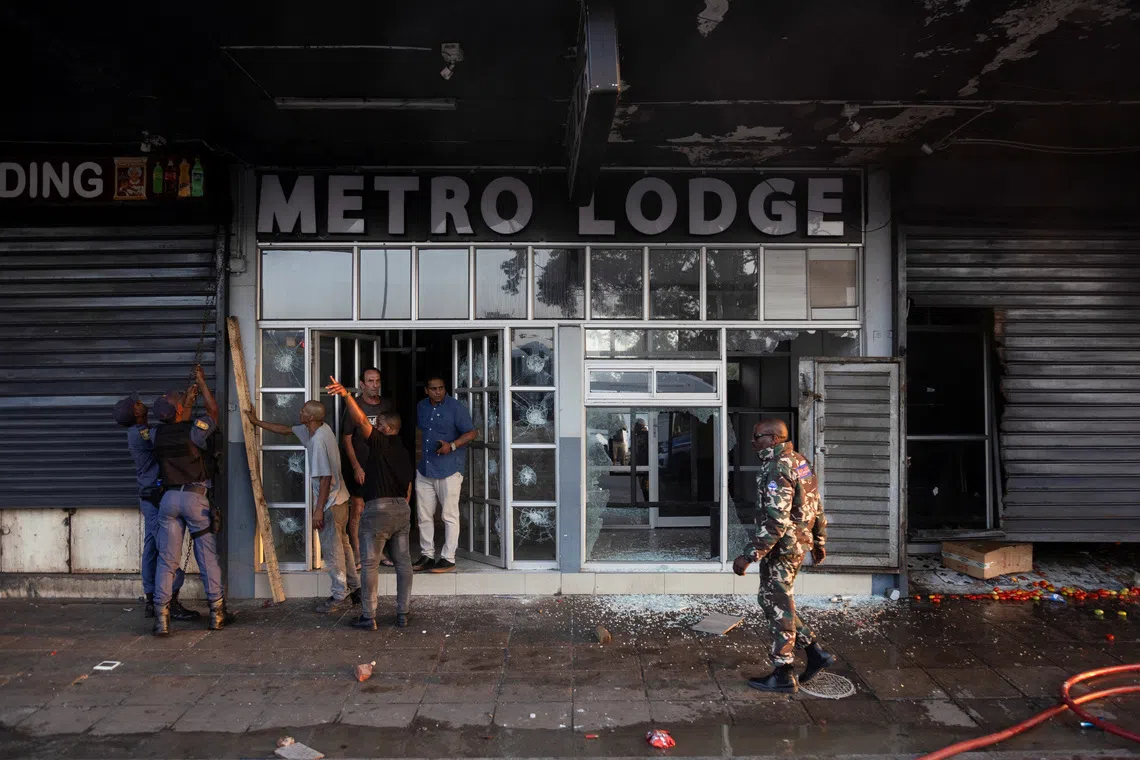 Police and security survey the damage done to a business during anti-immigrant protests in Durban, South Africa, on Oct 8.