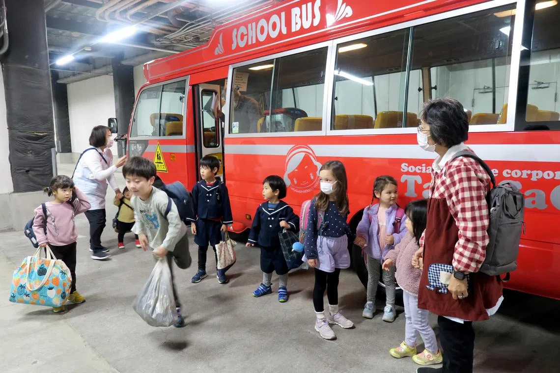 Children alighting from a school bus, which drops off and picks them up at childcare facilities in Japan's Nagareyama city. 