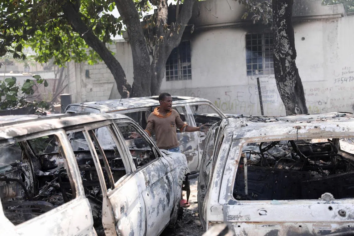 FILE PHOTO: A man reacts next to the charred remains of vehicles near the presidential palace, after they were set on fire by gangs, as violence spreads and armed gangs expand their control over the capital, in Port-au-Prince, Haiti, March 25, 2024. REUTERS/Ralph Tedy Erol/File Photo